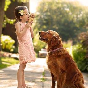 Girl eating ice cream cone with dog