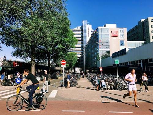 Bikes and commuters line an Amsterdam street mid-day